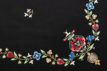The closeup of the detail of traditional norwegian vest-coast embroidery ornament, called Jelsa,  on the black woolen fabric