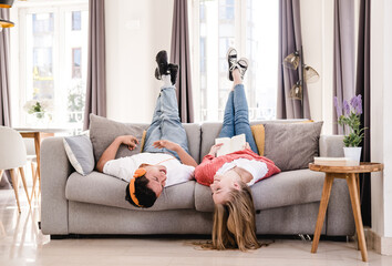 Young couple relaxing and spending time together while laying on the couch at home.