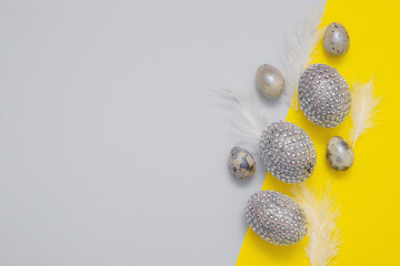 Top view of easter eggs in rhinestones and sequins on paper backgrounds in trendy colors with copy space