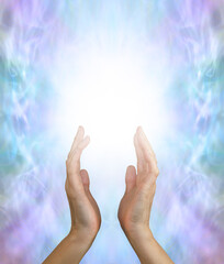 Sending out gentle spiritual healing energy  - female hands reaching up into a white energy field against a jade green purple energy formation background and copy space
