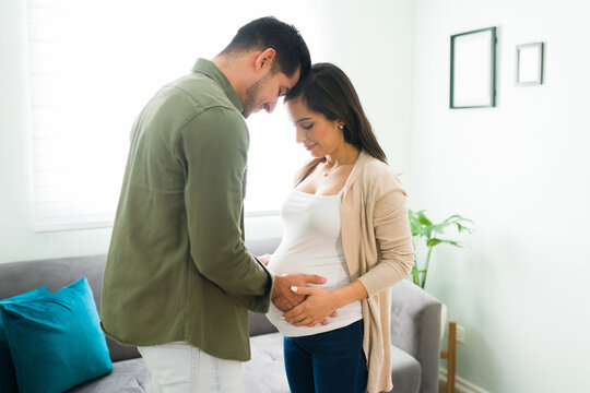 Adorable pregnant wife and husband holding hands an touching the belly