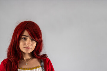 Full length young female attractive model in a studio with a white background, the model is wearing a red medieval costume with red auburn hair