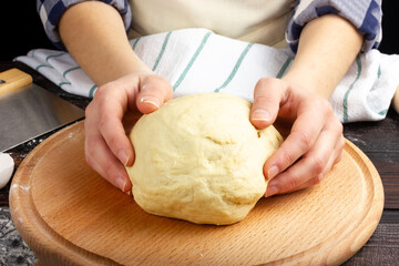 Women's hands are holding pastry. Dough preparation process. Work at the bakery. Rustic style.