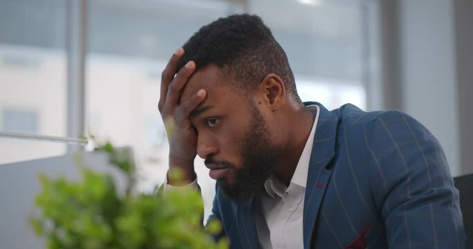 Close up of stressed and upset african man with laptop working at office