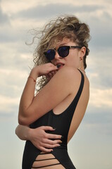 beautiful girl at the sea in a swimsuit and glasses sunbathes on the beach