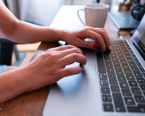 Young brunette woman working and learning from home with a cup of coffee next to her and her notebook