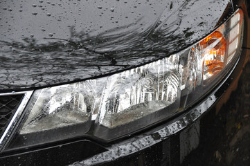 Detail of car headlights lamp, black modern car front lamp and raindrops