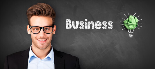 businessman in front of a blackboard with message BUSINESS