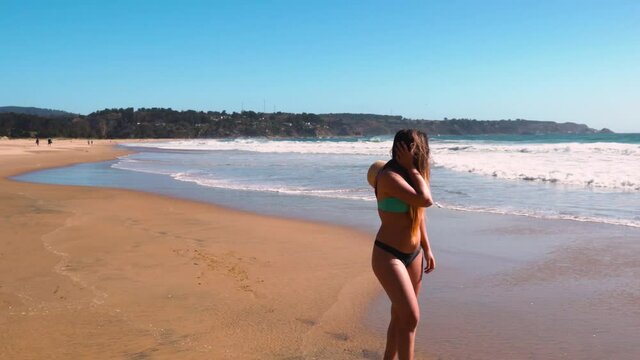 Beautiful brunette girl walking in the beach at Quintay in Valparaiso Chile on a sunny day