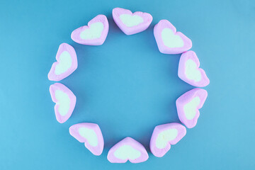 Pink heart-shaped marshmallow isolated on blue background.
