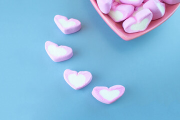 Pink heart-shaped marshmallow isolated on blue background.