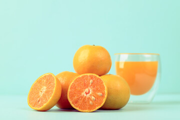 Fresh tangerine orange fruit and juice in glass on color background
