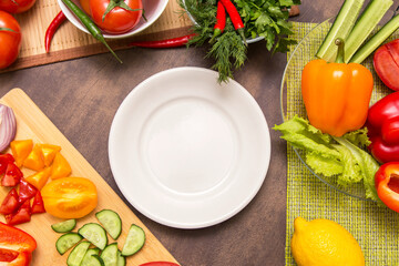 Different vegetables for cooking and empty white plate. Diet, fasting, vegan, vegetarian, healthy raw food concept