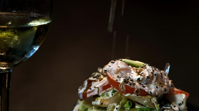 The chef decorates the salad with mayonnaise and spices . She sprinkles the salad with black sesame or cumin seeds. close-up.