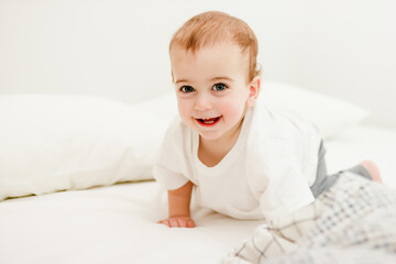 crawling baby in white tshirt on bed at home