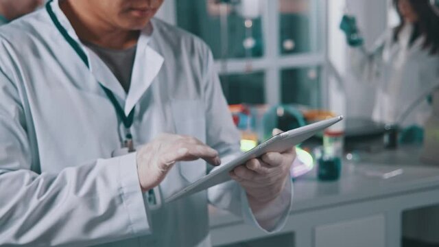 Close up hands man professional expert working in medical laboratory performing research with digital pc tablet computer. Pharmacy, microbiology, industry, biology, technology, doctor. Slow motion