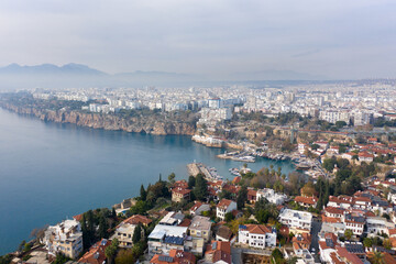 Fototapeta na wymiar Aerial panoramic view of the Antalya city. Mediterranean sea, and the coast of Antalya. Old town Kaleici, Yacht Marina, mountains and cloudy sky in the background. Aerial drone shooting. TURKEY