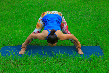 Fototapeta na wymiar Women practice yoga on the lawn, in the park, LUANNAN COUNTY, Hebei Province, China