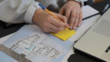 Male hands drawing on the plan with a pencil and rule on the table.