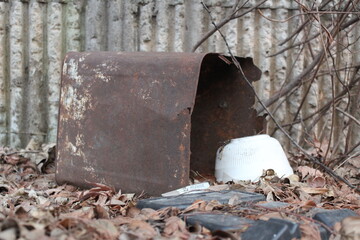 Too rusty empty ironclad and dirty trash on fallen leaves.