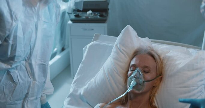 Covid 19 infected patient with oxygen mask lying on bed in quarantine room