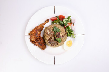 Beef Biryani Tehari with boiled egg coriander leaf garnish chicken curry pot roasted leg tomato cucumber onion chili coriander salad on white plate set over white background