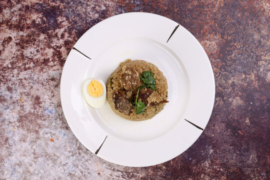 Beef Biryani Tehari cooked in mustered oil with boiled egg coriander leaf garnish on white plate over rustic rustic marble stone background