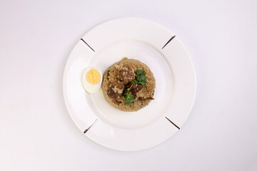 Beef Biryani Tehari cooked in mustered oil with boiled egg coriander leaf garnish on white plate over white background