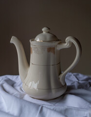 beautiful old tea pot or coffee maker. With a beige background on a white cloth.