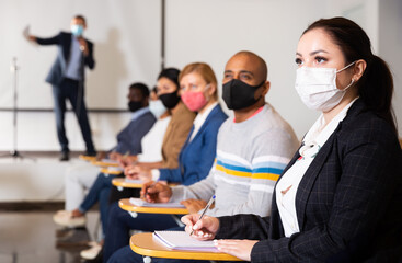 Confident young businesswoman in protective mask to prevent viral infection attending business seminar