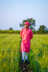 Naklejka na ściany i meble Young indian farmer walking at green wheat field
