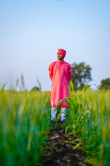 Naklejka na ściany i meble Young indian farmer standing at green wheat field