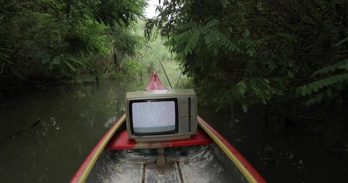 Canoeing in the wild with an old TV set, narrow passage in the reed, idyllic natural green lush environment in summer