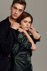 Man hugs from behind a woman romance studio relationship gray background