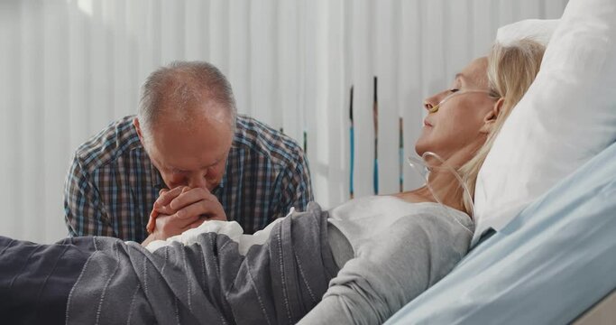 Upset senior man visiting wife in coma in hospital