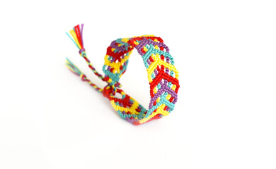 Tied woven friendship bracelet with bright colorful pattern handmade of thread on white background