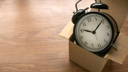 An alarm clock on a brown box on a wooden background.