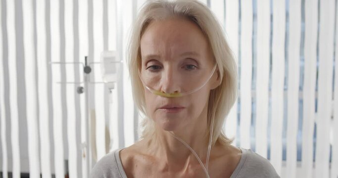 Close up portrait of female patient with nasal cannula staying in hospital room alone
