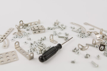 children's iron constructor with nuts and screws and a screwdriver on a white background
