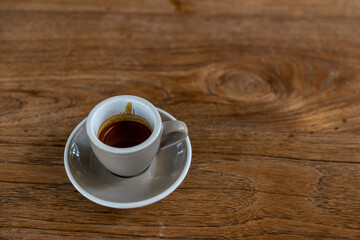 black drip coffee in glass cup. Cup of espresso coffee. Grey cup of black coffee on grey wooden desk or table.