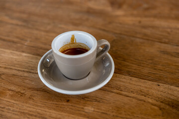 black drip coffee in glass cup. Cup of espresso coffee. Grey cup of black coffee on grey wooden desk or table.