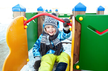 A cheerful child plays on the Playground on a winter day.