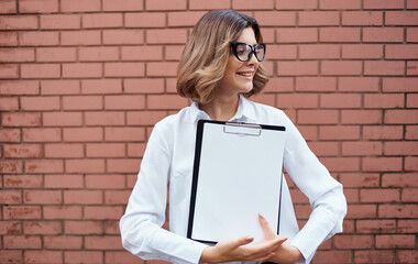 Business woman with documents near a brick building on the street