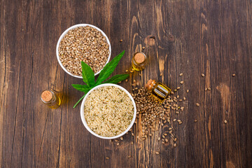 Organic hemp seeds and cannabis leaf on wooden background