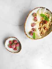 Healthy breakfast. Fresh granola, muesli with yogurt and berries on marble background. Top view. Copy space. Granola with raspberries. muesli with pear and raspberry. Place for text.