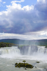 a beautiful cloud is located over the Godafoss waterfall, water spray rises up