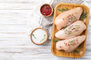 Chicken fillet with herbs and spices on white wooden table flat lay. Chicken meat with ingredients for cooking. Top view, copy space