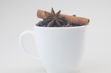 Coffee cup with beans, anise and cinnamon on white background.