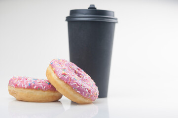 Two tasty donuts with disposable coffee cup  on white background