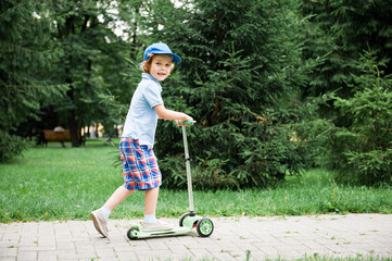 A child rides in the park on a scooter.